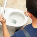 Person holding a toilet lid open for bathroom plumbing preparations ahead of holiday gatherings by A & W Plumbing.
