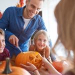 Father and kids carving pumpkins for Halloween; A & W Plumbing and Heating, Inc. offers seasonal family activity ideas.