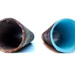 Image of two pipes: a rusty metal pipe and a clean blue plastic pipe, highlighting plumbing material contrast.