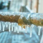 Icicles on a metal railing, featuring winter frost and droplets, relevant for A & W Plumbing services.