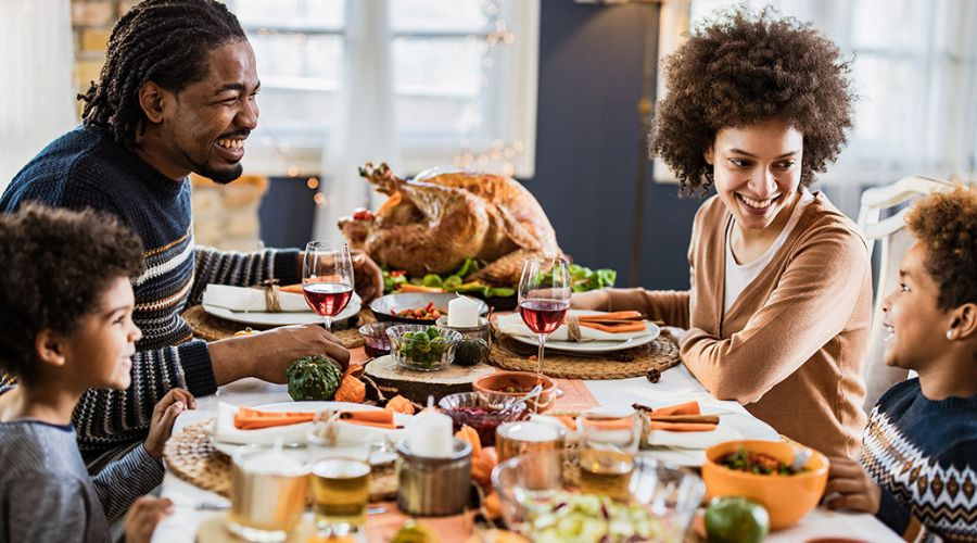 Family gathered around a dining table with turkey and side dishes, showcasing a cozy celebration, amidst festive decorations.