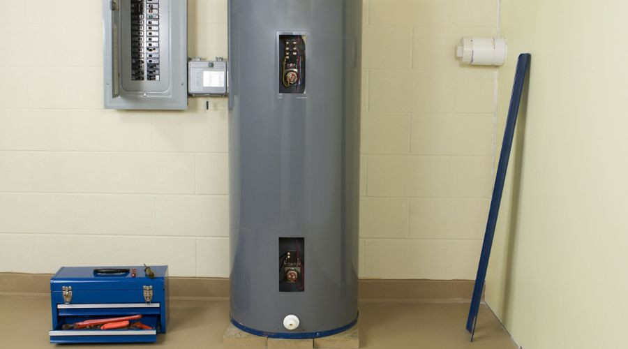 Utility area featuring a gray water heater, electrical panel, and blue toolbox for plumbing maintenance.