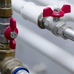 Metal pipes and red valve handles showcasing plumbing components for A & W Plumbing and Heating, Inc. maintenance tips.