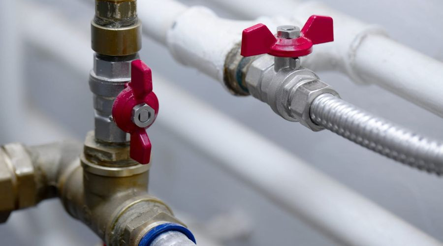 Brass and metal valves with red handles in plumbing system by A & W Plumbing and Heating, Inc. for maintenance readiness.