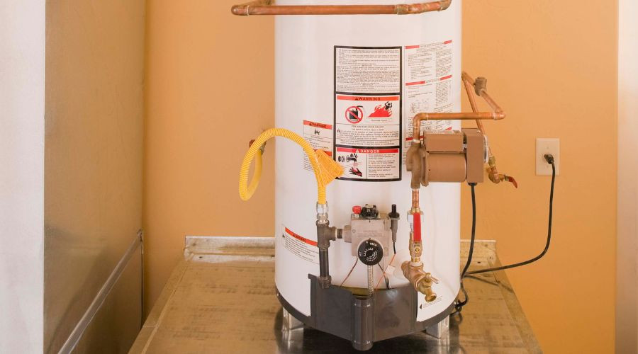 White cylindrical water heater with copper pipes and gas supply line for plumbing and heating services.