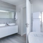 A modern bathroom interior featuring a minimalist design with a focus on white and gray tones.