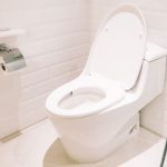 Modern toilet in a clean bathroom setting, emphasizing proper maintenance and disposal habits to prevent clogs and plumbing issues.