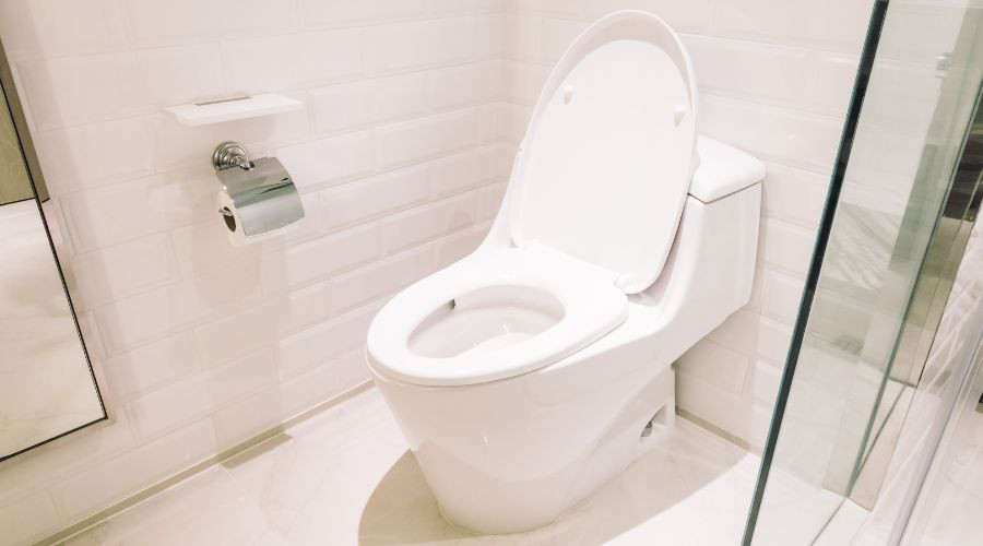 Modern flush-mounted toilet in a clean white tiled bathroom, a plumbing solution by A & W Plumbing and Heating.